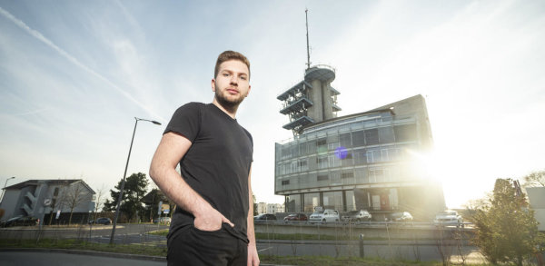 Le Glandois Marvin Grimm, âgé de 21 ans, est l'auteur d'une pétition pour un moratoire sur la 5G. Le voici au pied du bâtiment Odyssea de l'EPFL, sur le toit duquel se trouve l'une des premières antennes 5G de Swisscom. (Photo: Sébastien Anex)